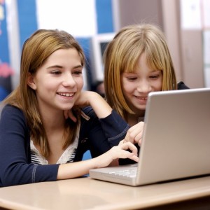 Two young girls working on a laptop in the classroom